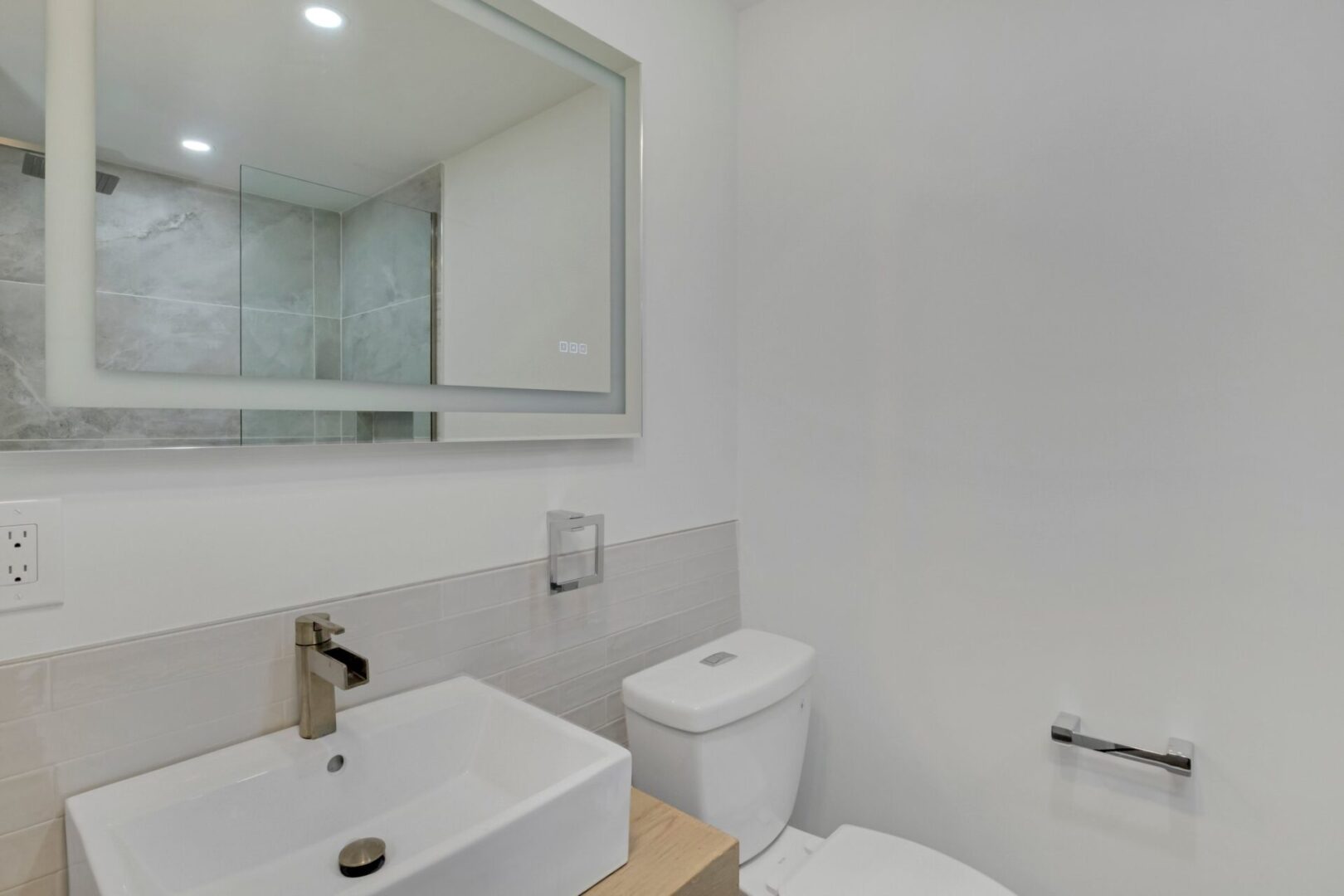 A bathroom with white walls and a mirror.