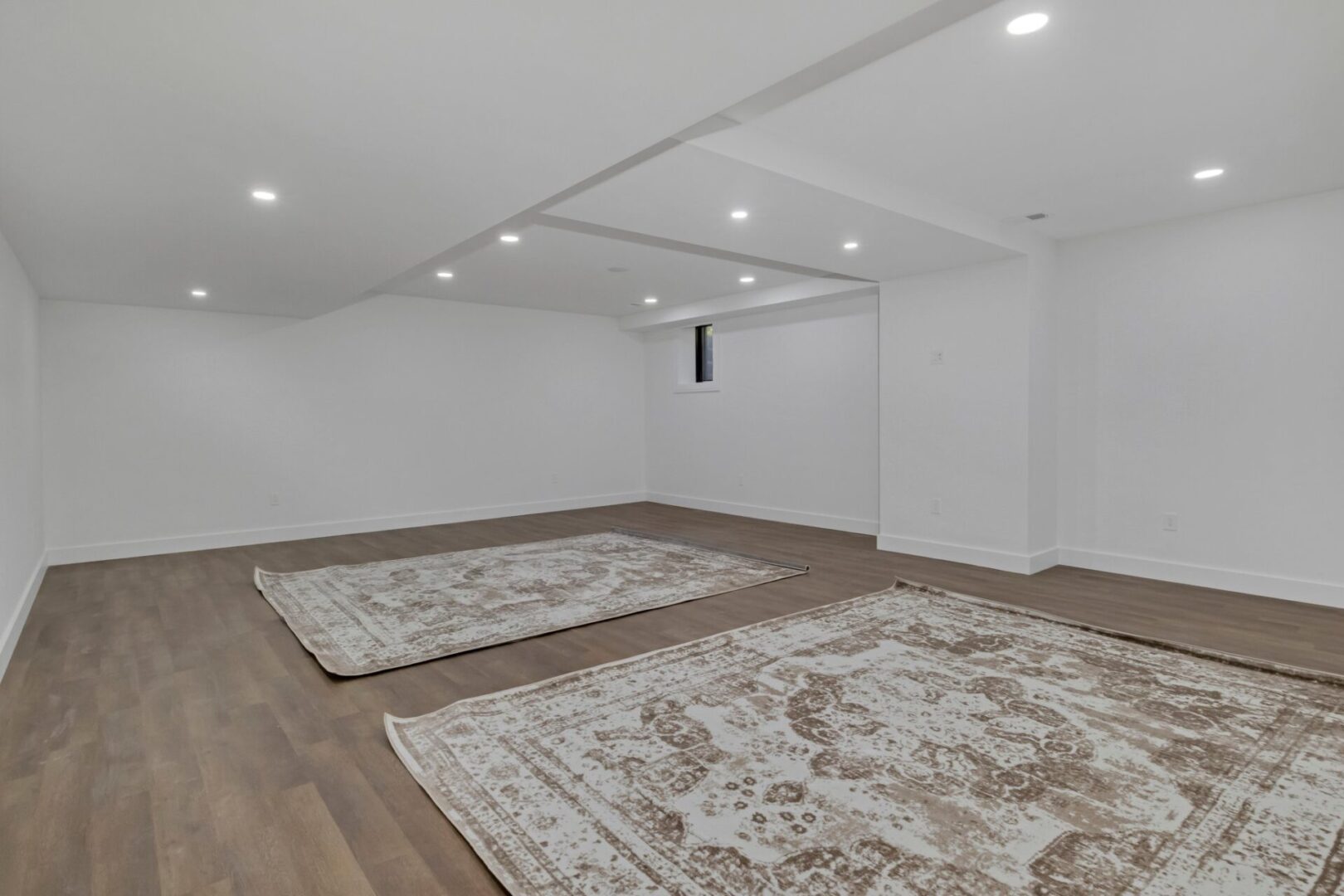 Two rugs in a room with white walls.