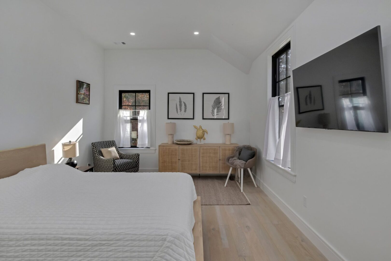 A bedroom with white walls and wooden floors.