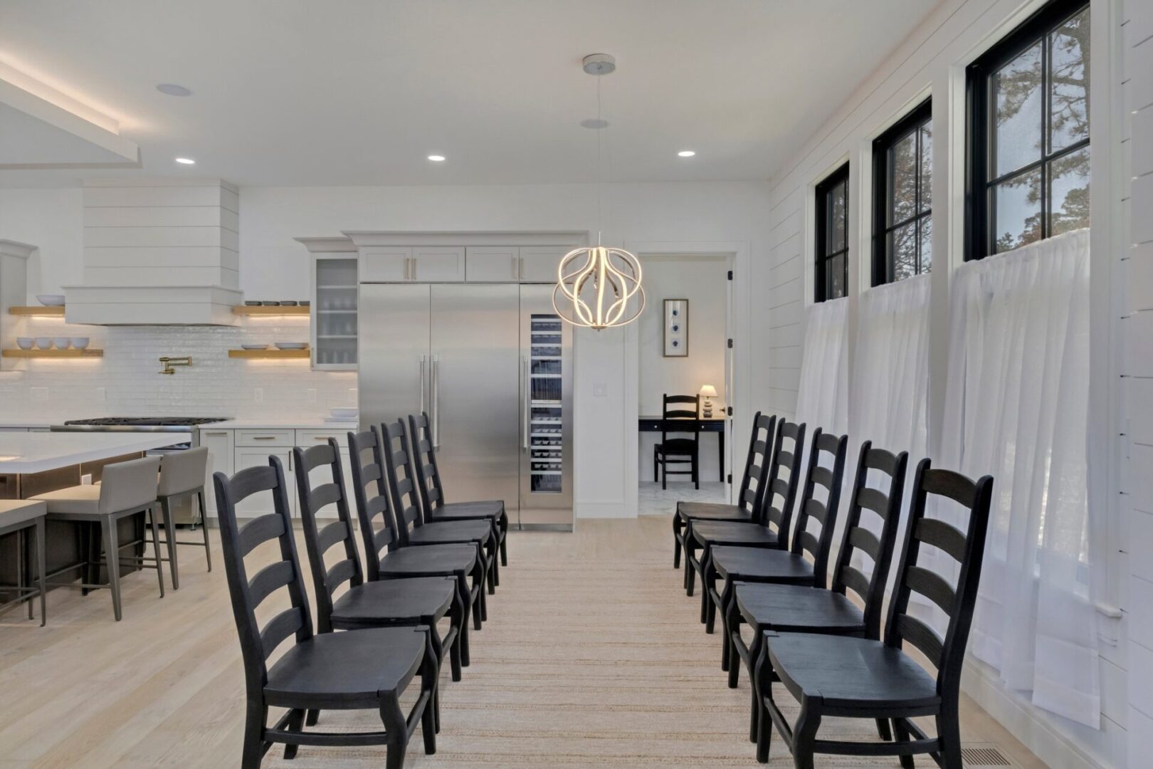 A long line of black chairs in front of a kitchen.