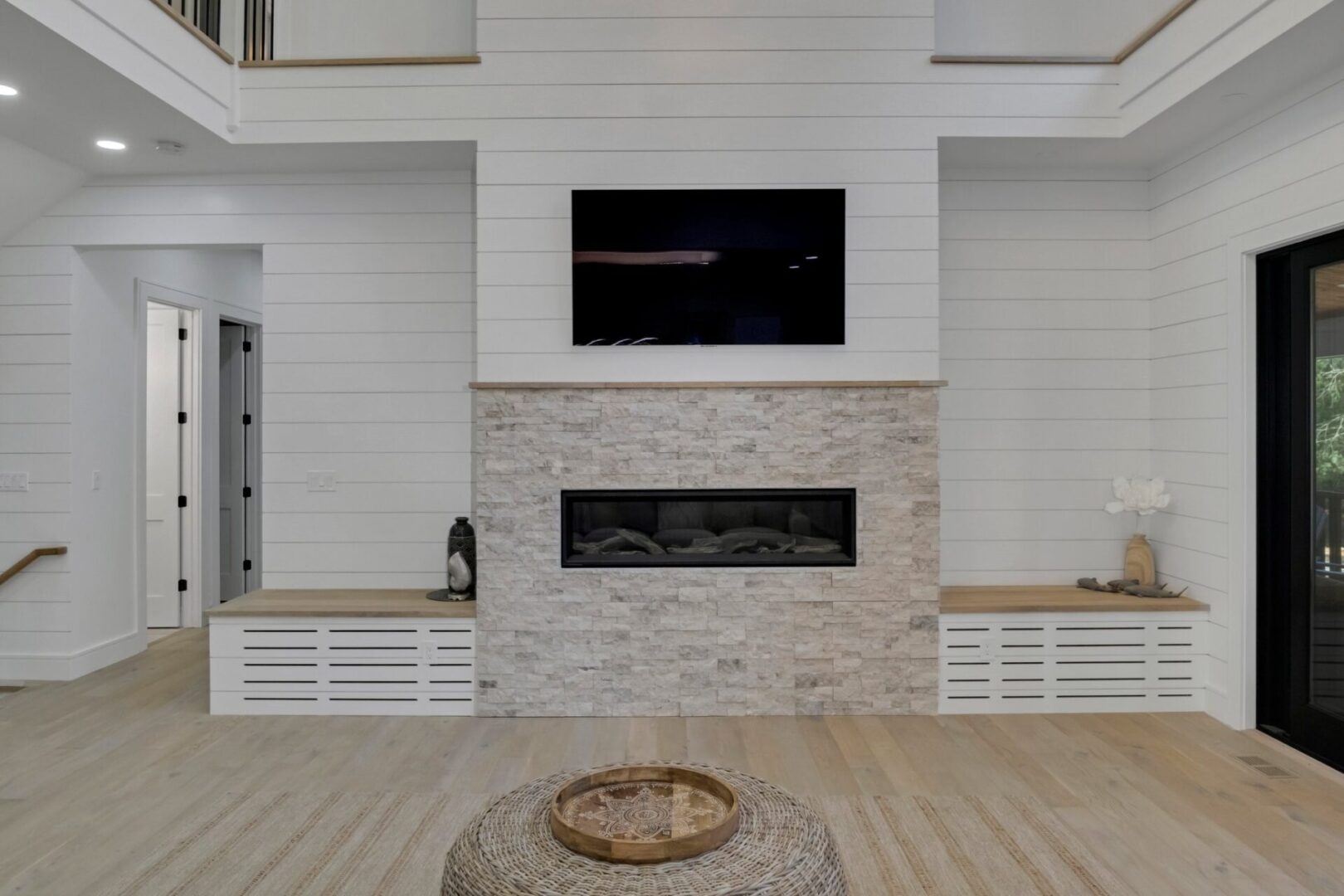 A fireplace with a tv above it and two wooden benches.