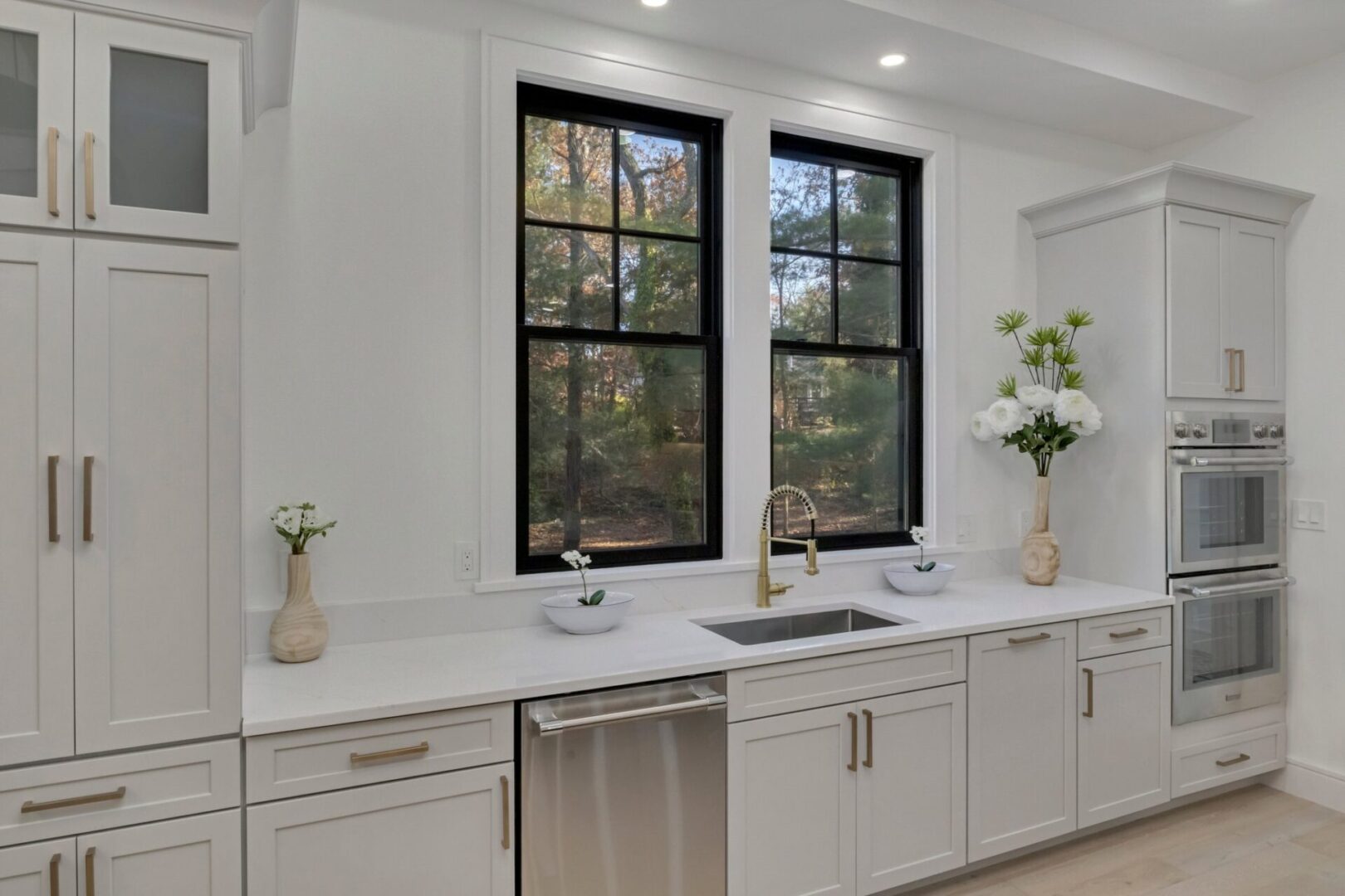 A kitchen with white cabinets and black windows.
